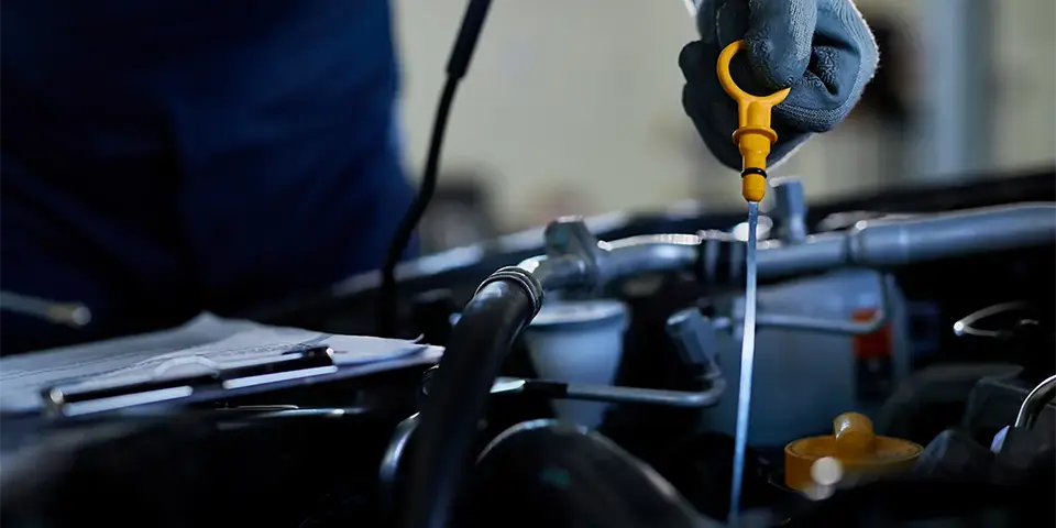 Mecânico segurando a vareta para medir o nível do óleo do motor.