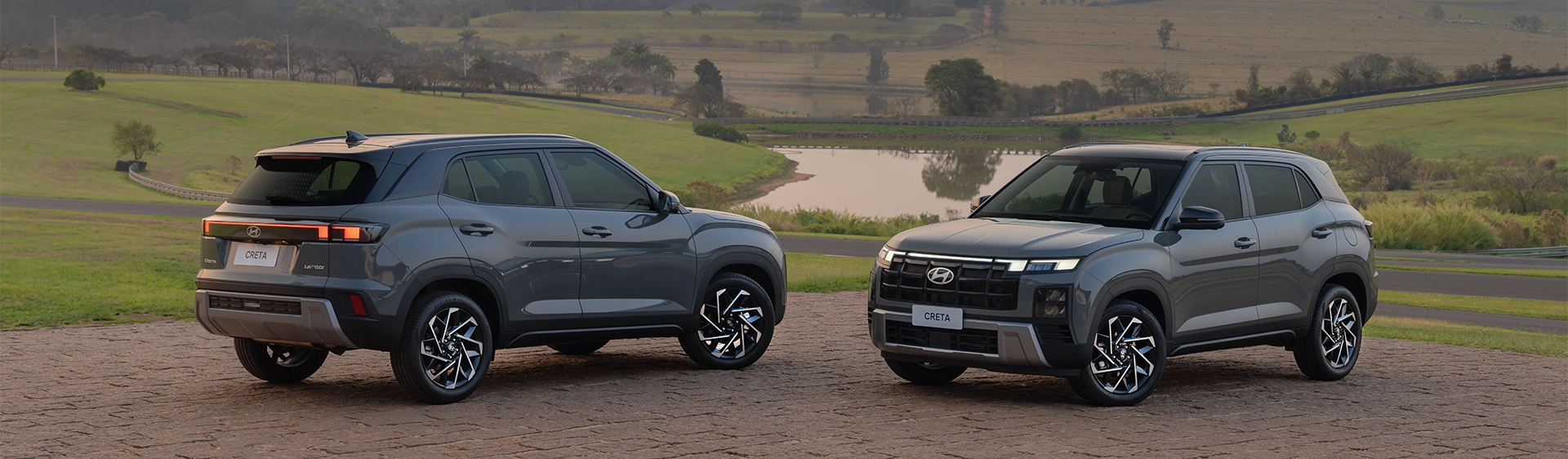 Dois Novo Hyundai CRETA estacionados lado a lado, com pôr do sol e paisagem natural ao fundo.