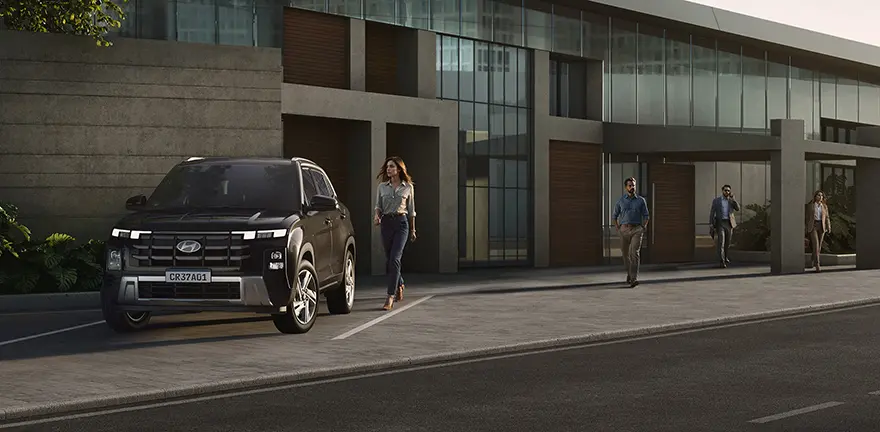 Modelo CRETA Comfort na cor preta estacionado na rua durante o dia com mulher caminhando ao lado.